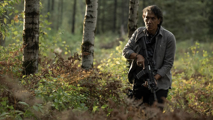 Michael Greyeyes armed and alert in the forest in 40 Acres