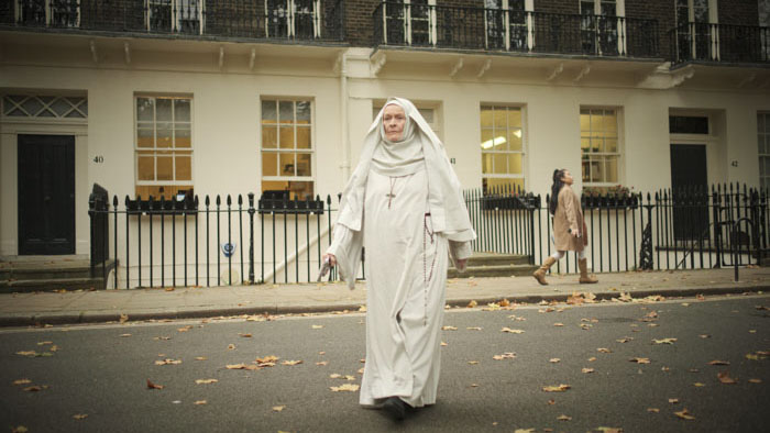 Elderly nun walking across a London street in Consecration (2025)