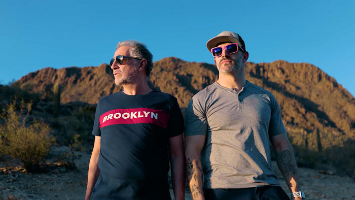 Vince Desi and team member of Running With Scissors standing in the desert with mountains in the background