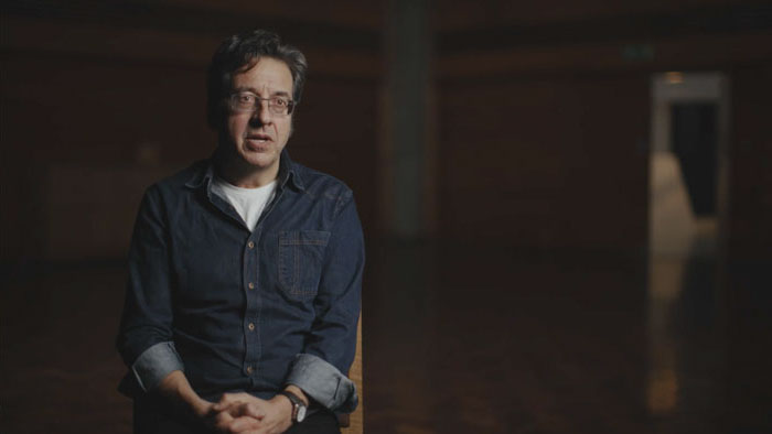 George Monbiot seated during an interview in The Invisible Doctrine documentary