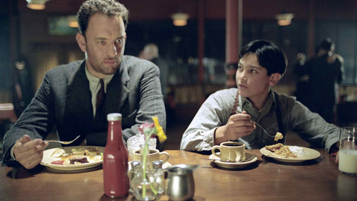Tom Hanks and Tyler Hoechlin at a diner in Road to Perdition, portraying father and son during a quiet moment