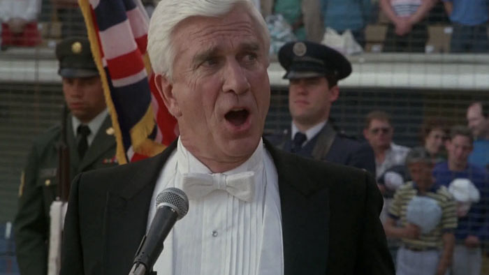 Leslie Nielsen sings the national anthem in a tuxedo during a baseball game in The Naked Gun