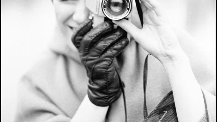 Sheila Turner Seed holding a camera in an archival black-and-white portrait from the late 1960s.
