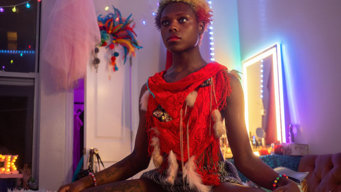 Nova sits in her colorful, neon-lit room in Alphabet Soup.