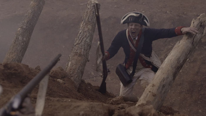 Revolutionary War soldier charges uphill during a battle reenactment in America’s Woman