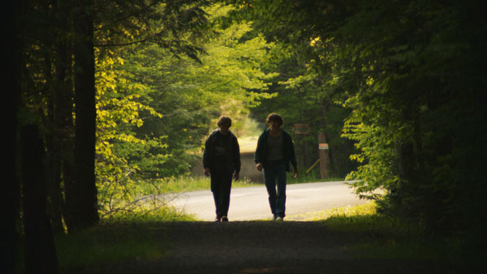 Two teenage boys walking down a forest road in Bleeding.