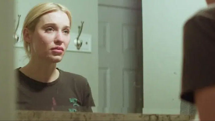 Ava stares into the mirror, reflecting on her struggles in Freak Off