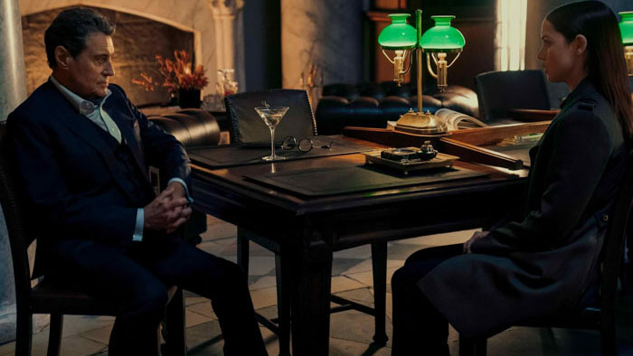 Ian McShane and Ana de Armas in a tense meeting scene from Ballerina (2025)