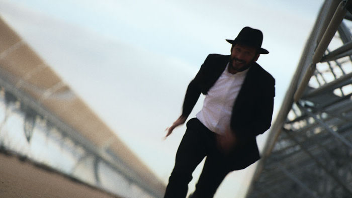 Rabbi Mo runs through an industrial solar field in a dramatic chase scene.