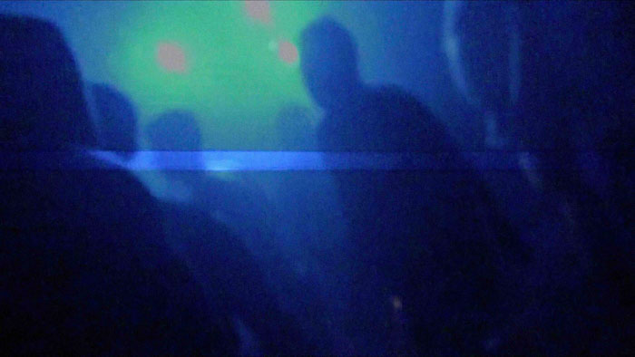 Silhouetted figures in neon blue haze from Guts and Glitz