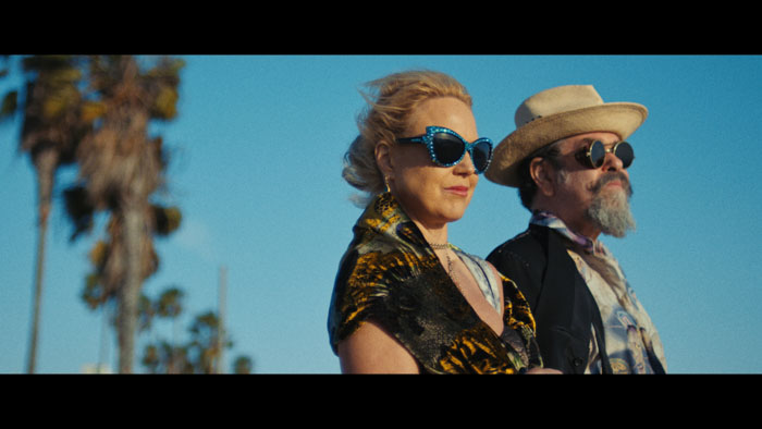 Whitney Ward and Joe Coleman in sunglasses walking under palm trees in Los Angeles in How Dark My Love