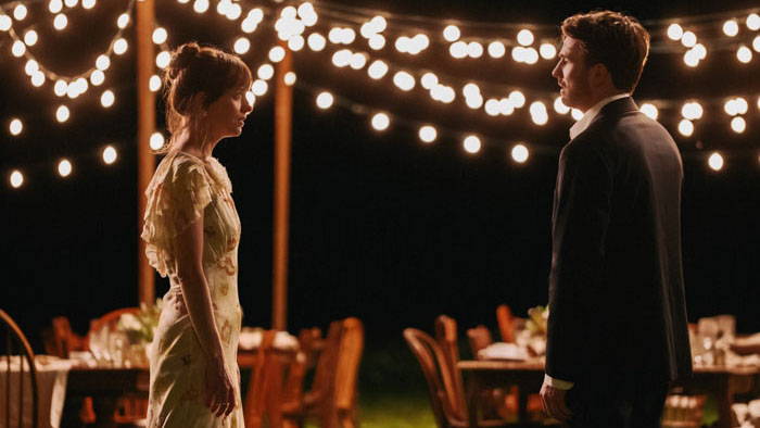 Dakota Johnson and Chris Evans face each other under string lights in The Materialists