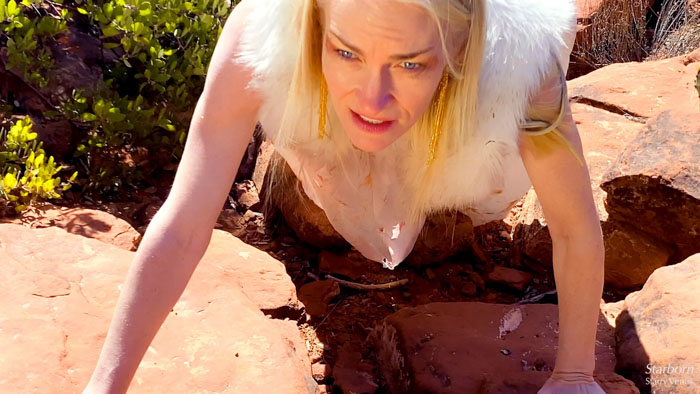 Alt Text:Andrea Wright crawls across red rocks as Divine Mother in Starborn