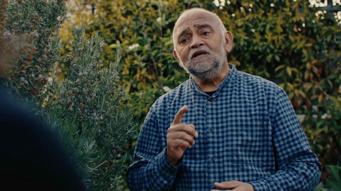 Professor Seva speaks passionately in a garden setting in That Time is Now