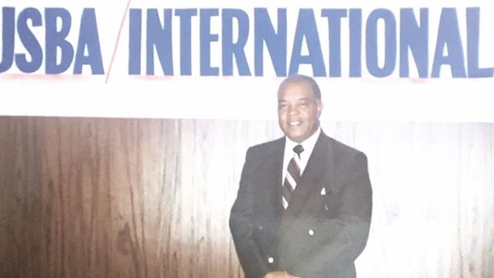 Robert W. Lee Sr. standing in front of a USBA/International banner