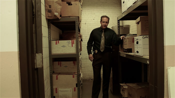 Commander Moran standing in evidence storage room with Gacy case files