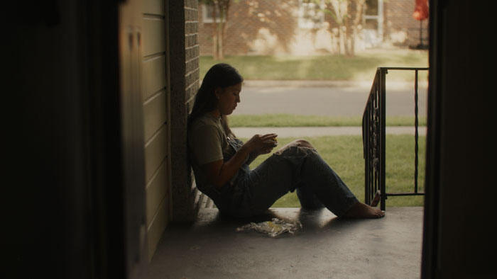 Woman sitting alone on a porch sewing in quiet reflection