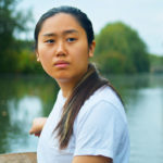 Valerie Kwok as Deji in Wild Swimmers, rowing on a quiet, eerie river