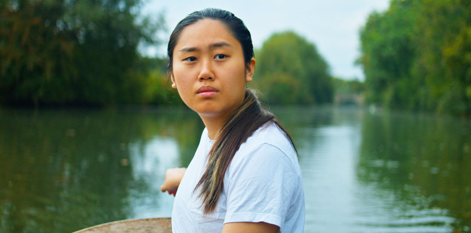 Valerie Kwok as Deji in Wild Swimmers, rowing on a quiet, eerie river