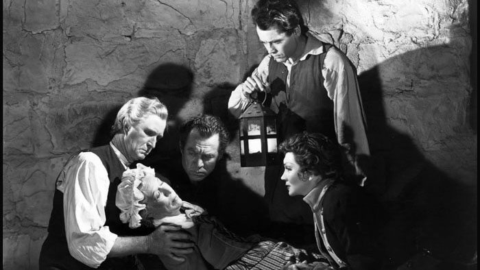 Frontier settlers gather in a tense moment from Drums Along the Mohawk