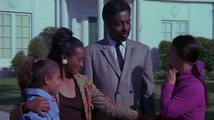Dr. Kinkade and his family greet a neighbor outside their new home in Abar, the First Black Superman