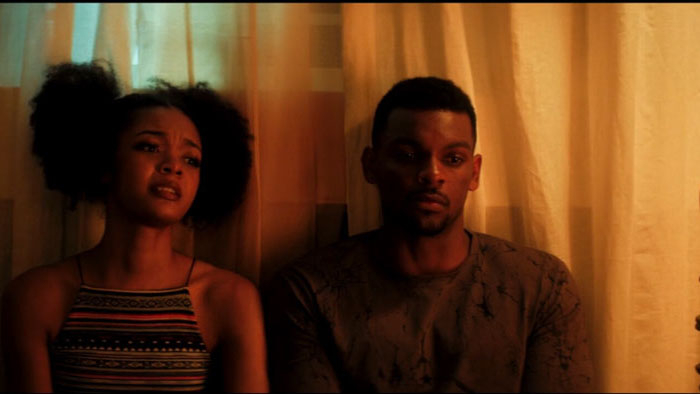 Julian and Crystal sit together in a dimly lit room, deep in conversation