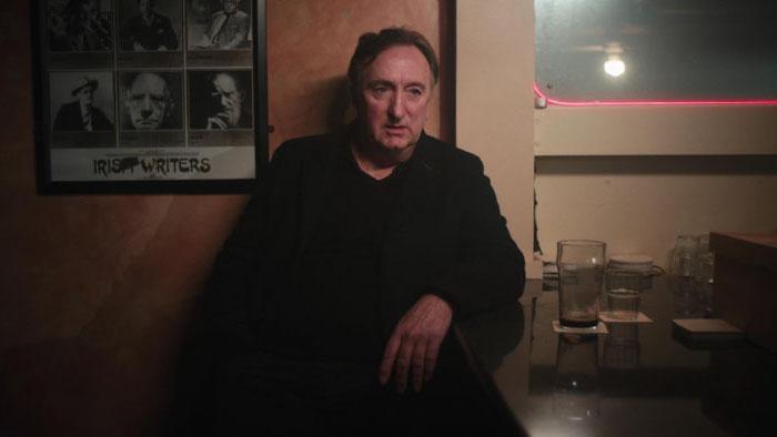 Peter Gowan sits at the bar beneath a cracked Irish Writers poster in Vanilla
