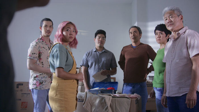 The family from No No Girl gathers around a table, reacting to the discovery of letters.