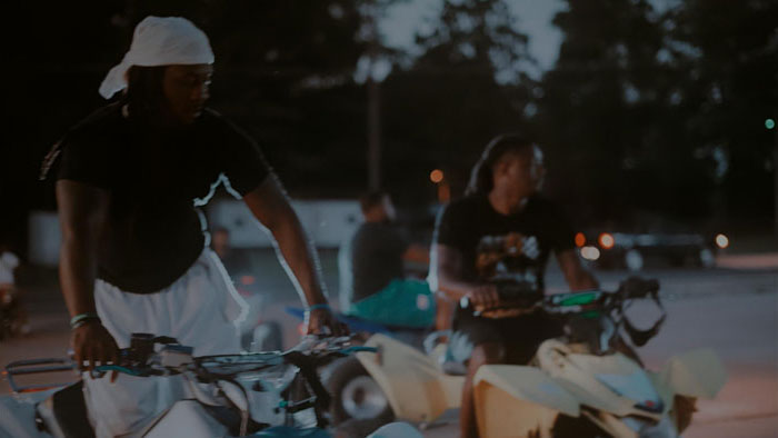 Two men riding ATVs at dusk in Village Uncut
