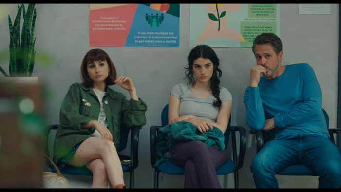 Ella Rubin, Thomas Sadoski, and Betsy Brandt sit in a waiting room in Adult Children.