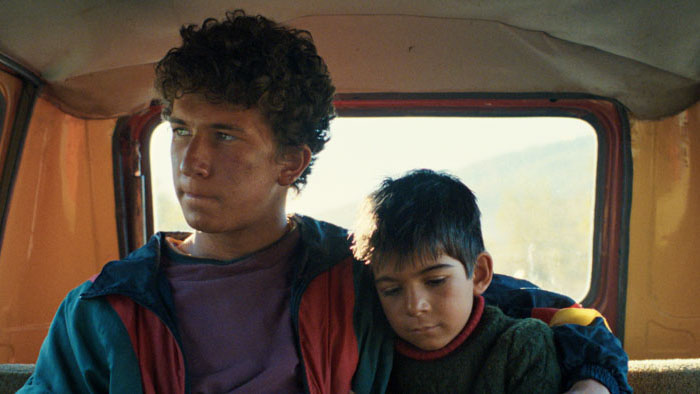 Ahmet sitting in a car with his younger brother in DJ Ahmet.