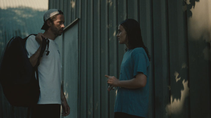 Julie talks to a man outside near a corrugated wall in Julie Keeps Quiet.