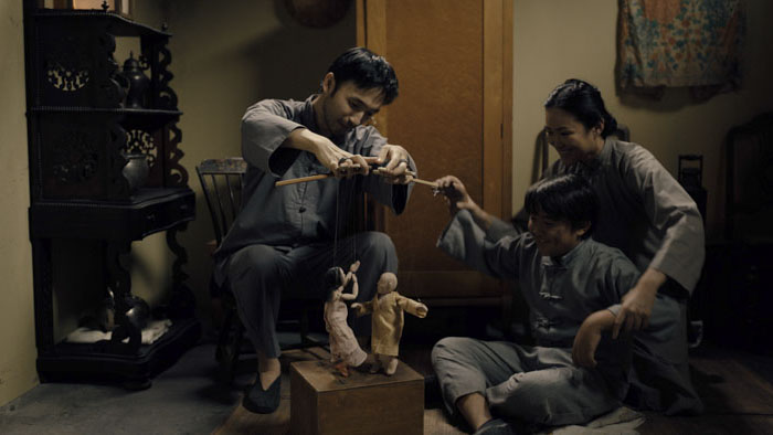 A Chinese family plays with puppets in a warm, dimly lit room in Site.