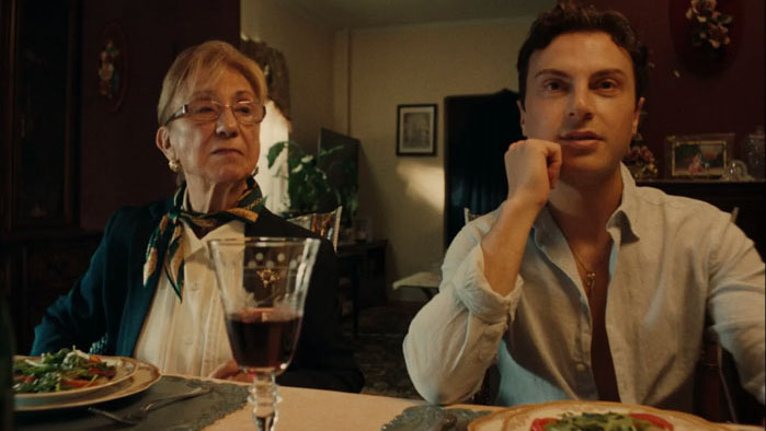 Dinner table scene from Sunday Sauce with elderly woman and young manTitle: Dinner Scene in Sunday Sauce