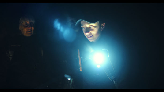 Daniel Lee Barnett searches for Bigfoot in the forest at night wearing a headlamp.