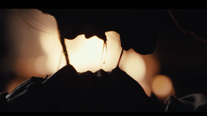 A vampire leans over a victim as blood drips between them in Bloodsuckers and the Grimoire.