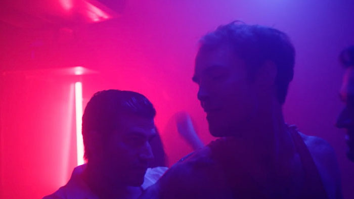 Taylor Ghrist and another man in a neon-lit nightclub scene from Dangling Carrot