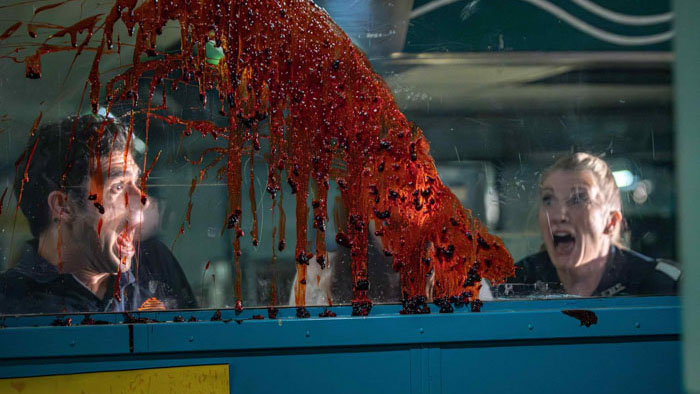 Screamboat scene showing two terrified ferry workers reacting to a bloody attack through a glass window.