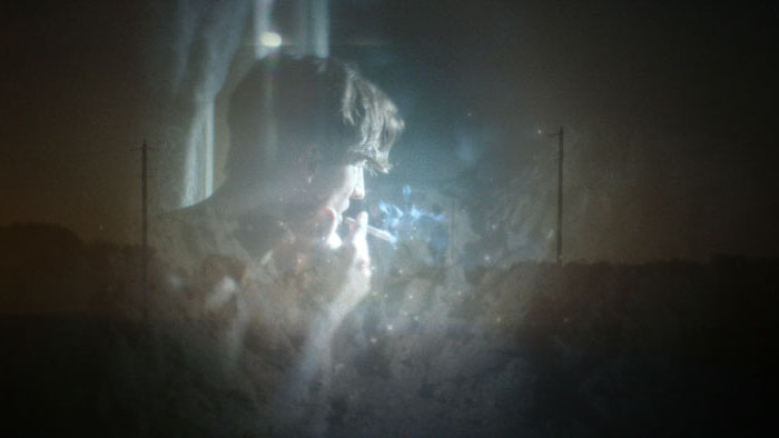 woman lying in the darkness with her face against the ground, illuminated by dim blue light.