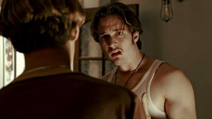 A tense scene from Letters of Love where Marko confronts Peter inside a dimly lit room.