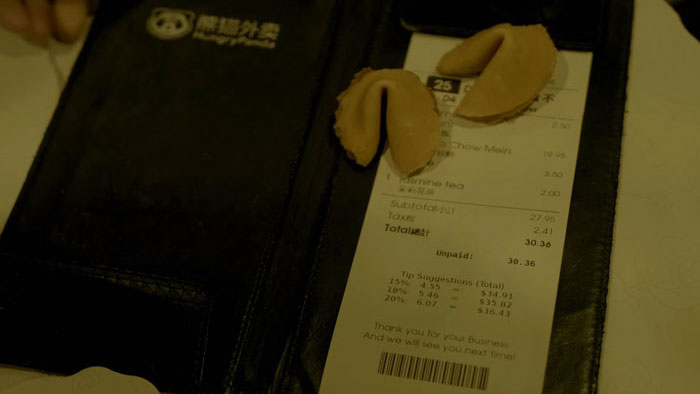 Fortune cookies resting on a restaurant bill from Nuclear Cookies