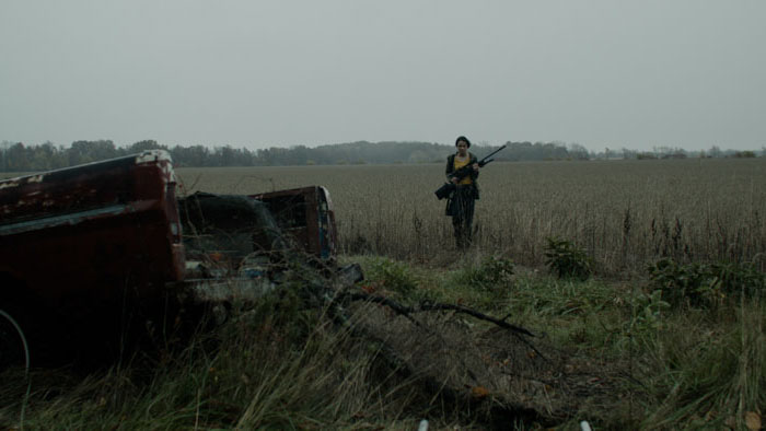 Grace stands in a bleak field holding a rifle in Honor’s Half-Life (2025).