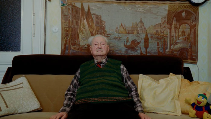 Erich Finsches sitting on a couch in his home during an interview setup.