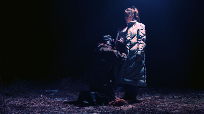 Amelia is confronted by a mysterious woman in the woods during a nighttime attack in Something of a Monster.