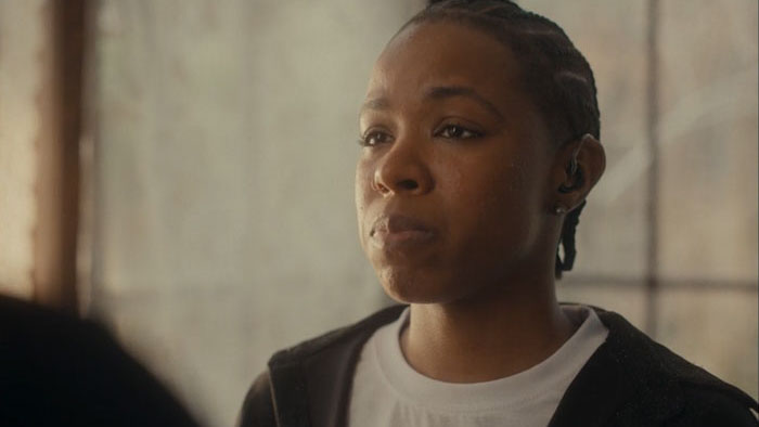 Andrea “Drea” Stoney stands quietly during the family repass in Them That’s Not (2025).