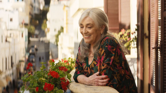 María Ángeles (Carmen Maura) smiles on her balcony above a Tangier street in Calle Málaga.