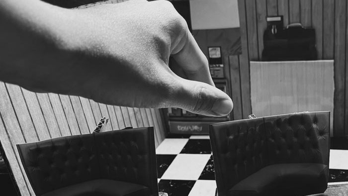 Hand manipulating miniature diner booth set in Clocking Out (2026)
