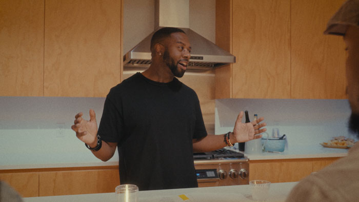 Mark Anthony Thomas speaking in a kitchen during the documentary short In Need of Seawater. 