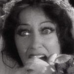 Close-up of Patricia Kelly (Gloria Swanson) in distress, gripping her head, in a dramatic moment from Queen Kelly.