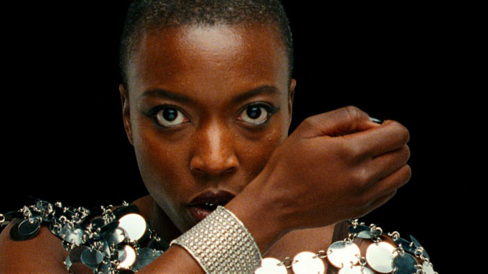 Celine Camara in Reflection in a Dead Diamond (2025), close-up with intense stare and glittering metallic accessories.